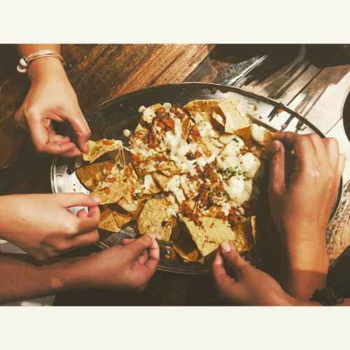 close up photography of people picking nachos chips