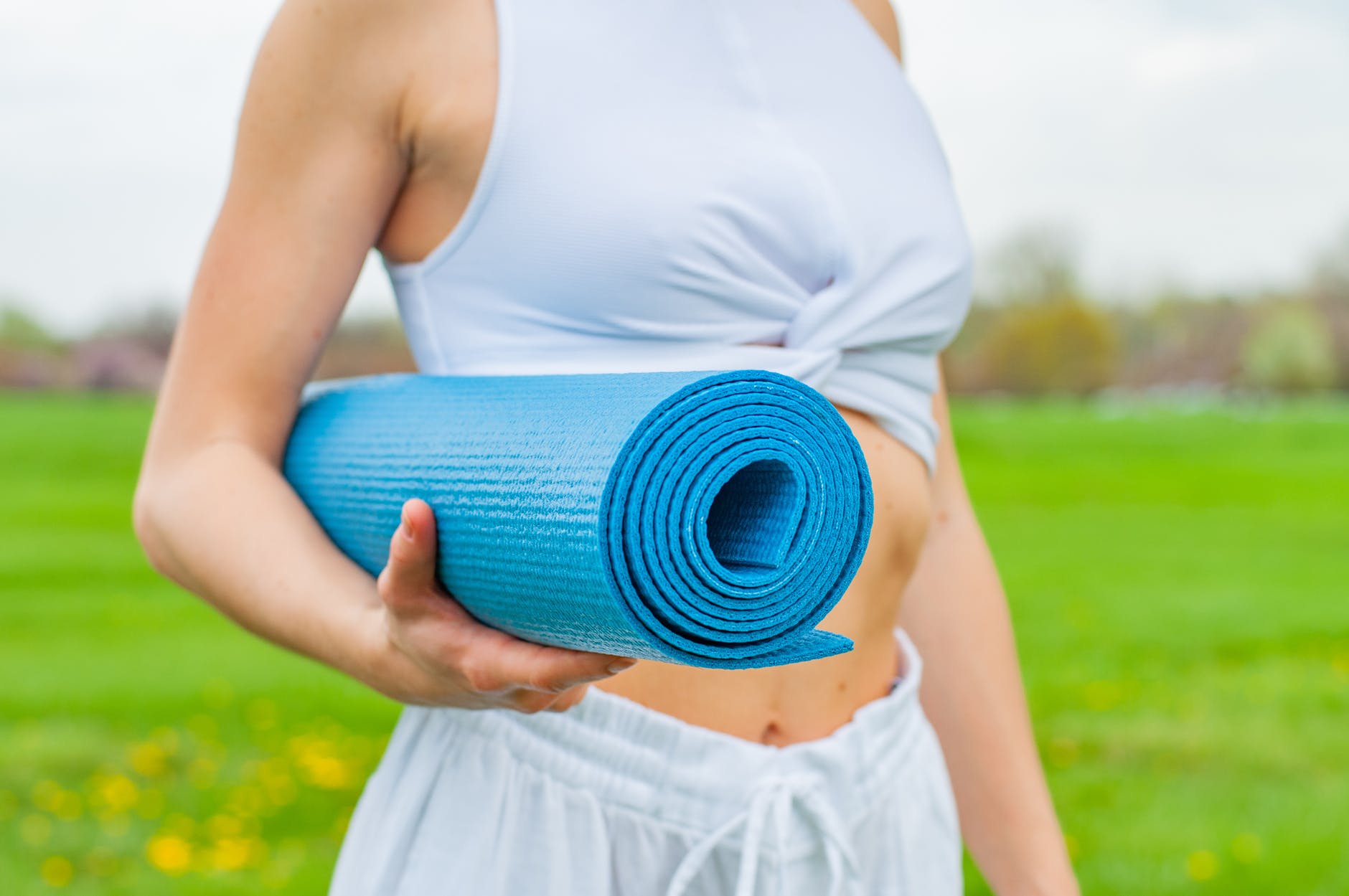 woman standing and holding blue yoga mat